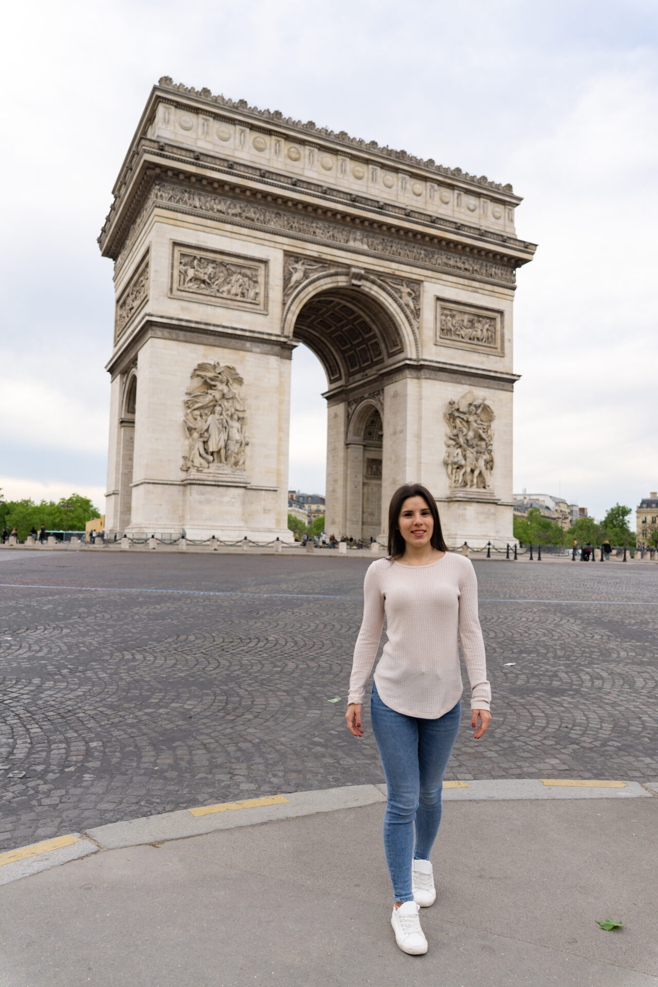Young woman tourist walking and behind the Triumphal Arch in paris